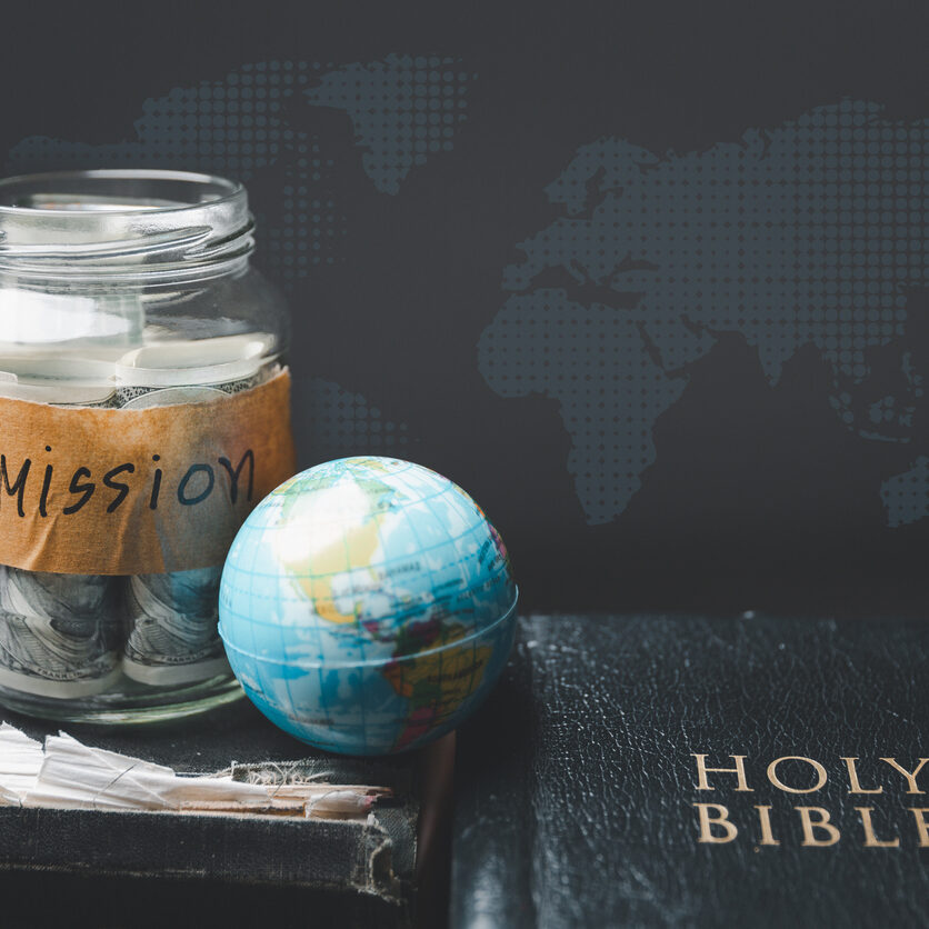 Savings jars full of money and globe with Holy Bible for mission, Mission christian idea. bible and book on wooden table, Christian background for great commission or earth day concept.