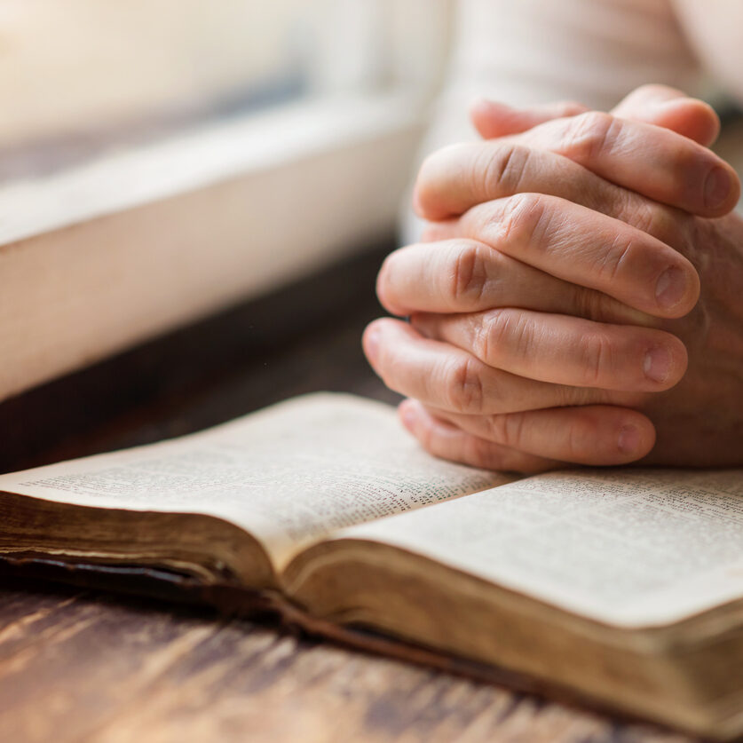 Unrecognizable woman holding a bible in her hands and praying